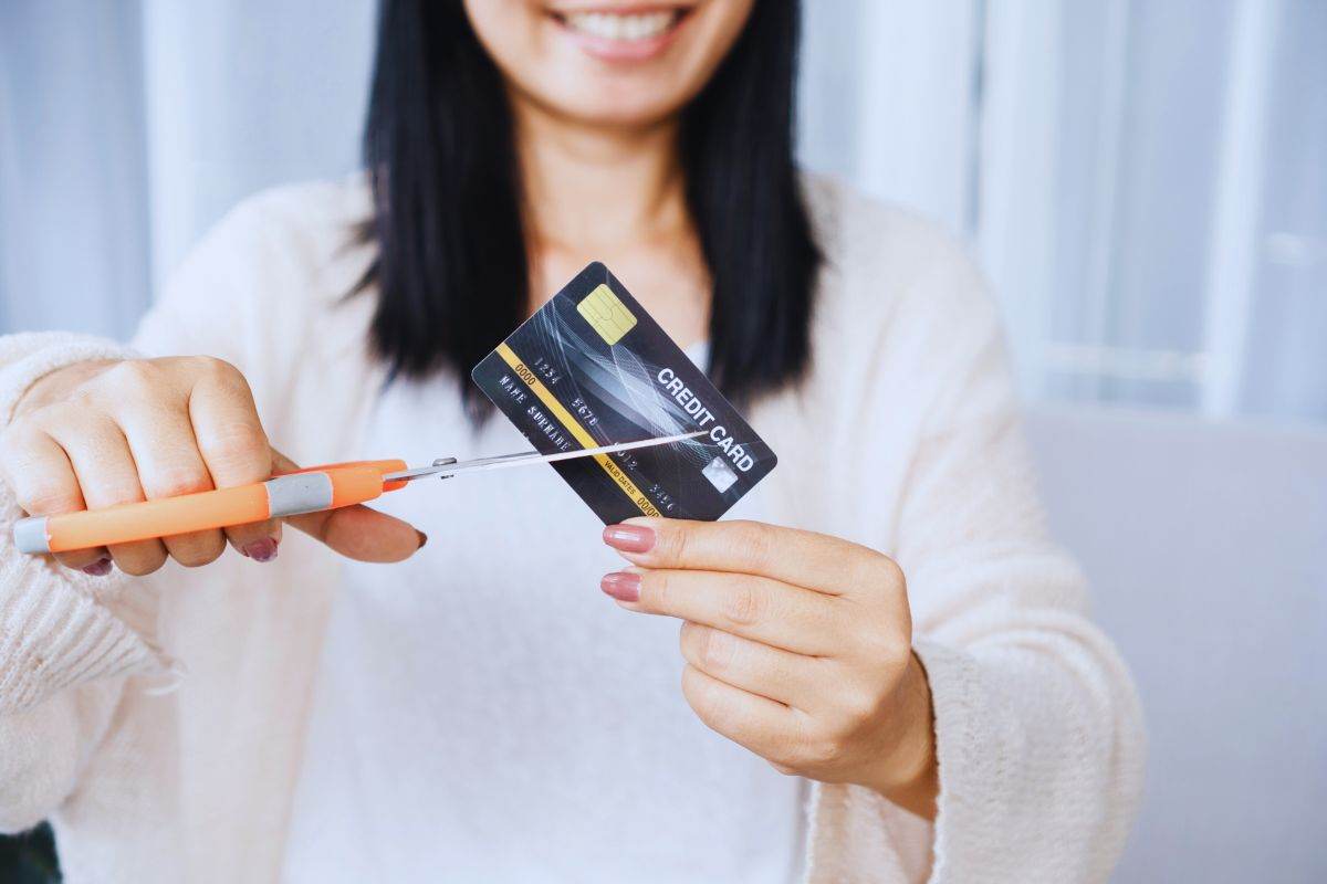 donna sorridente taglia una carta di credito